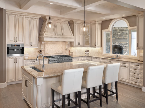 Travertine Backsplash and Travertine Herringbone Set up Inlay with Cambria Berkeley Countertop and Overhang Island Top and English Cream Paint Maple Cabinets Cambria Berkeley Countertop and Overhang Island Top with English Cream Paint Maple Cabinets, Travertine Backsplash and Travertine Herringbone Set up Inlay, Porcelain Flooring and Transparent Kitchen Pendants